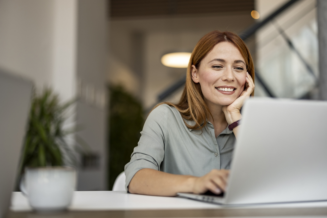 Zufriedene Mitarbeiterin arbeitet entspannt am Laptop