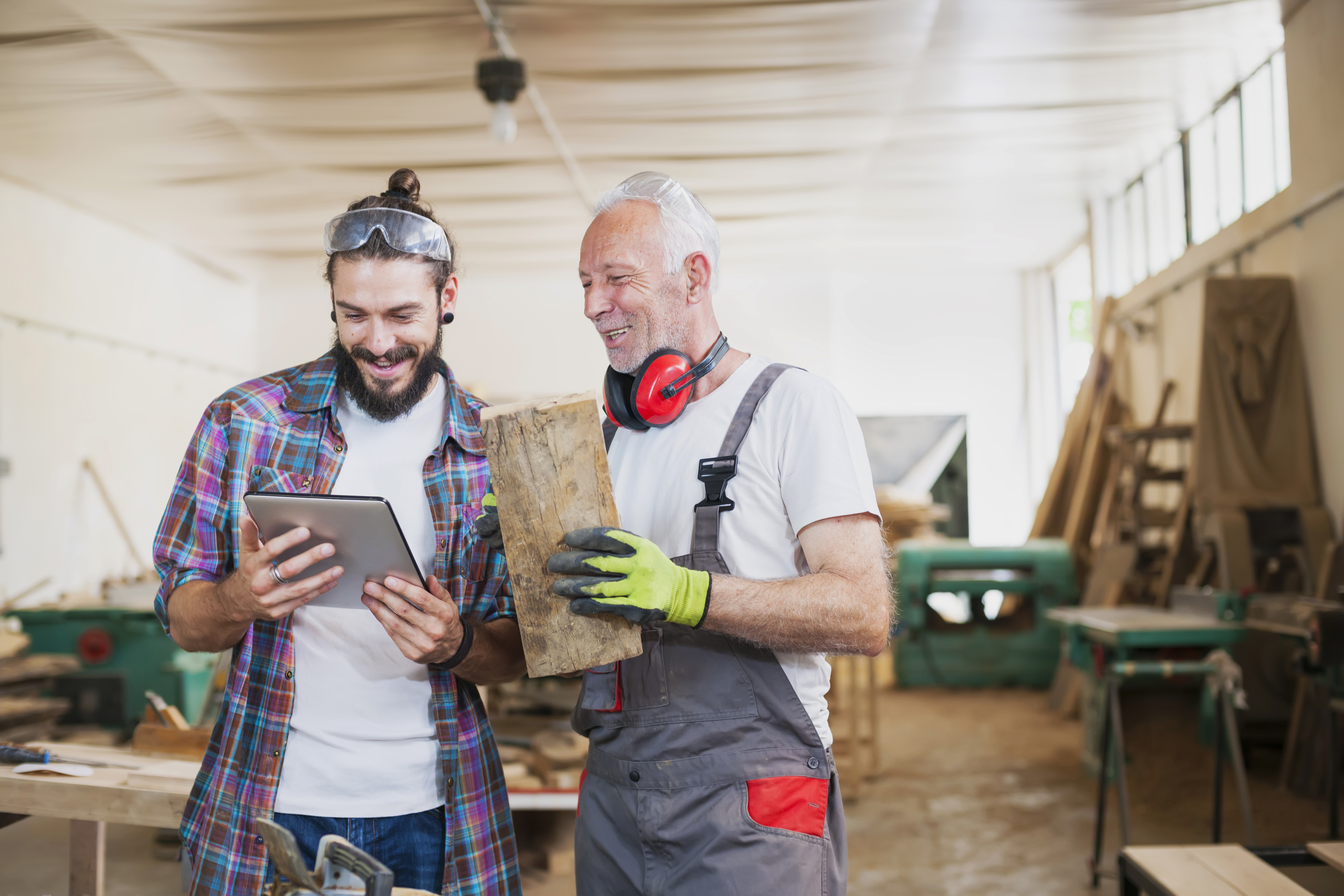 Handwerksmeister und Mitarbeiter besprechen Lagerbestand am Tablet